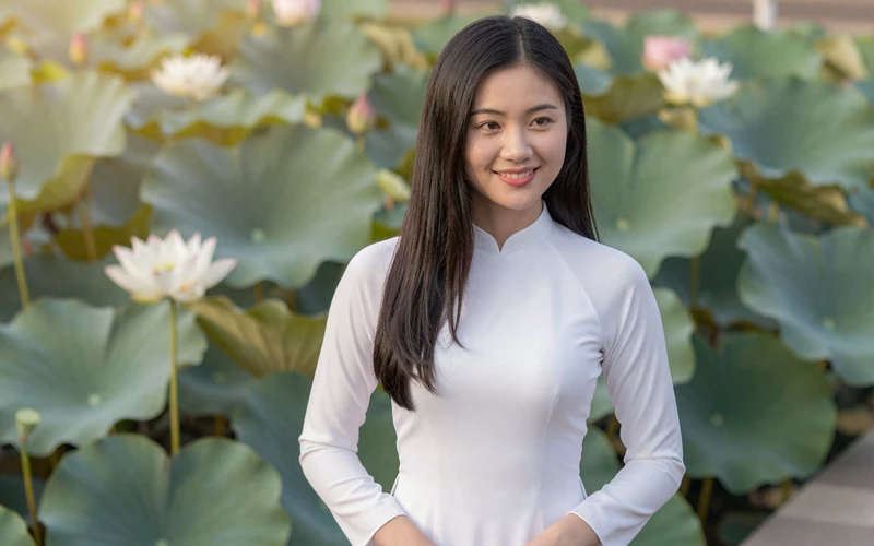 Beautiful Vietnamese woman in ao dai dress in garden representing Southeast Asian dating culture