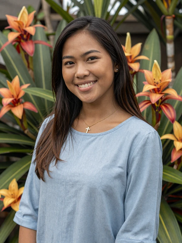 Timorese woman wearing a blue blouse and gold cross necklace representing educated East Timor singles seeking meaningful relationships