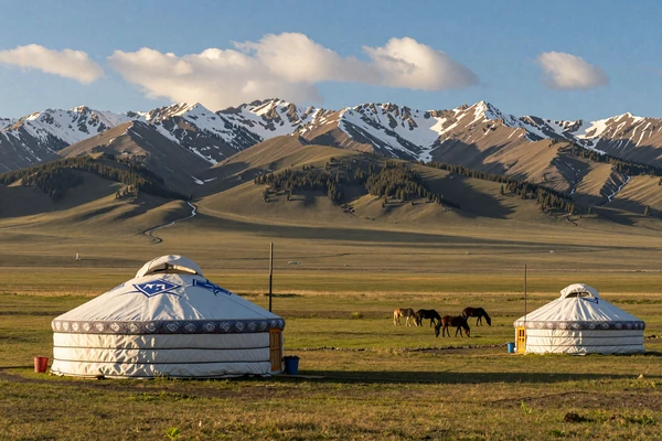 Traditional Kazakh yurt on the vast steppe with Tien Shan mountains representing nomadic heritage of Kazakhstan