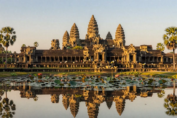 Ancient Angkor Wat temple complex in Cambodia at sunrise reflecting in lotus pond with lush tropical surroundings